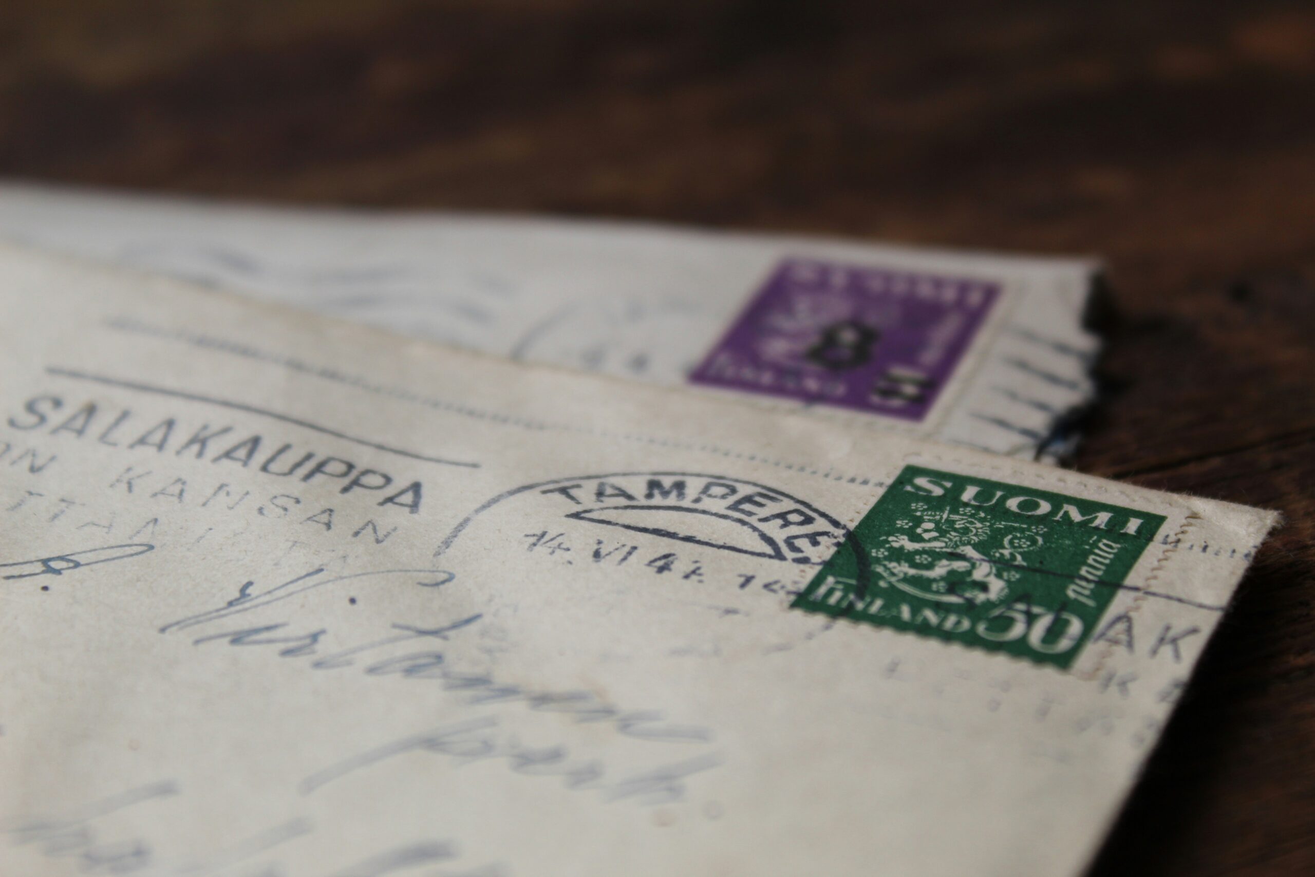 Zwei alte Briefe mit finnischen Briefmarken und handgeschriebener Adresse, im Fokus liegt ein grüner SUOMI-Stempel.